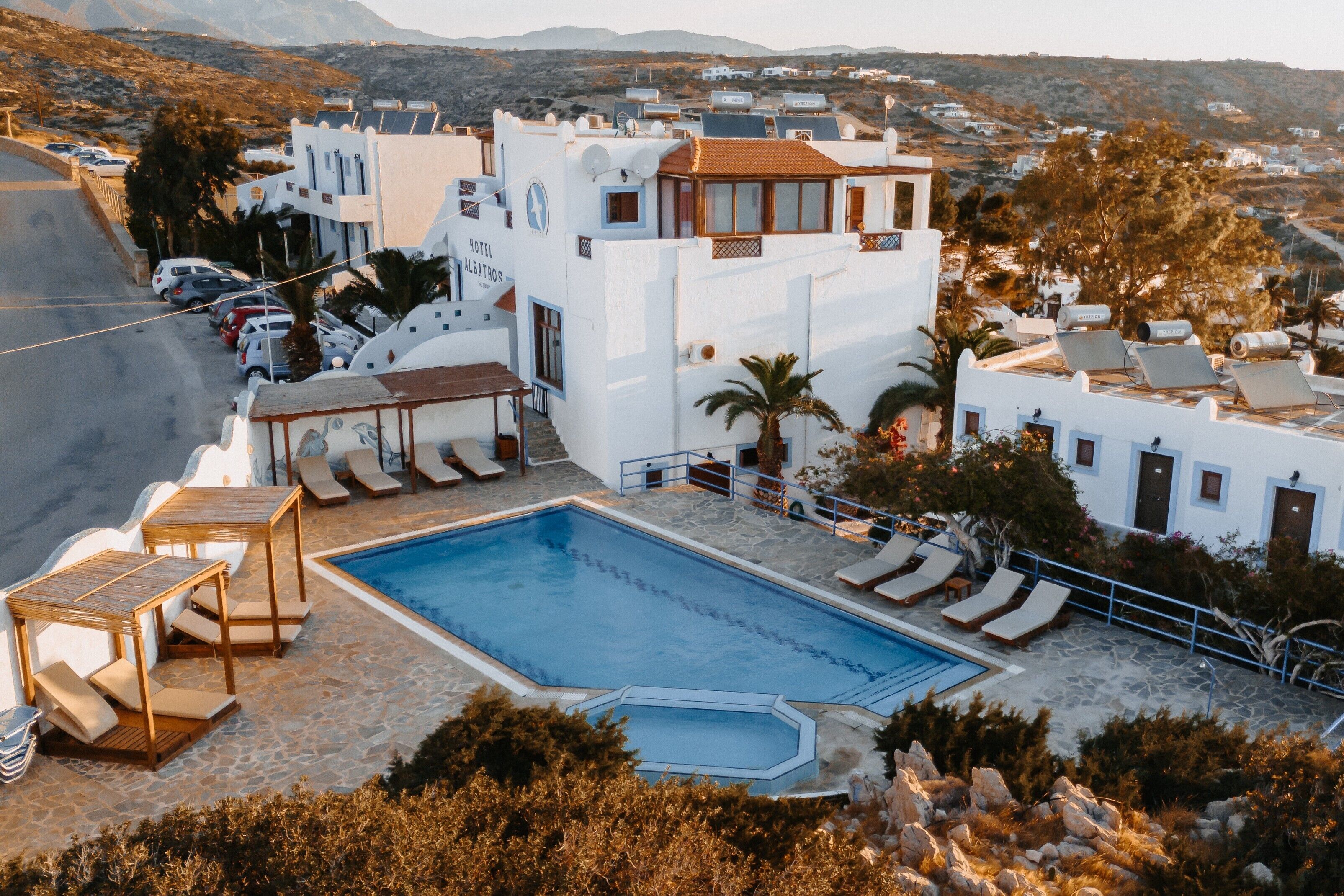 Un hotel con piscina, sillones de descanso y vistas del paisaje circundante.