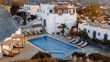 Un hotel con piscina, sillones de descanso y vistas del paisaje circundante.
