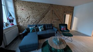 A modern living room with a sectional sofa, a round coffee table, and a green rug. - Apartment “Epprechtstein” with Wi-Fi (Kirchenlamitz)