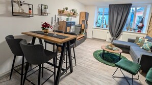A modern living space with a dining area, a sofa, and a window with curtains. - Apartment “Epprechtstein” with Wi-Fi (Kirchenlamitz)