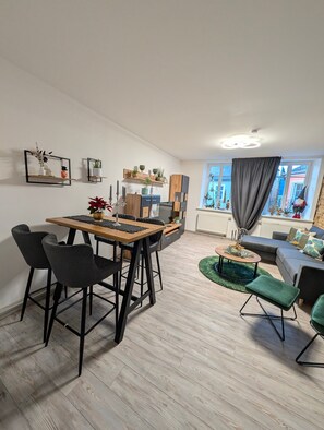 Ein stilvoller Wohnbereich mit Essbereich, einer Couch und einem Fenster mit Vorhängen.