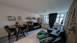 A modern living room with a dining area, a sofa, a TV, and a window with curtains. - Apartment “Epprechtstein” with Wi-Fi (Kirchenlamitz)