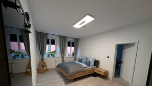 A modern bedroom with a bed, bedside table, and a window with curtains. - Apartment “Epprechtstein” with Wi-Fi (Kirchenlamitz)