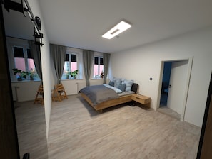 Un dormitorio moderno con cama, mesita de noche y ventana con cortinas.