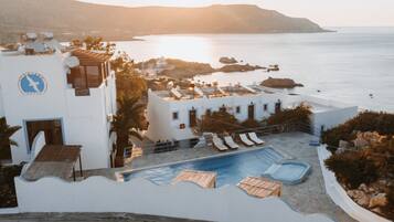 A hotel with a pool, lounge chairs, and a view of the sea.
