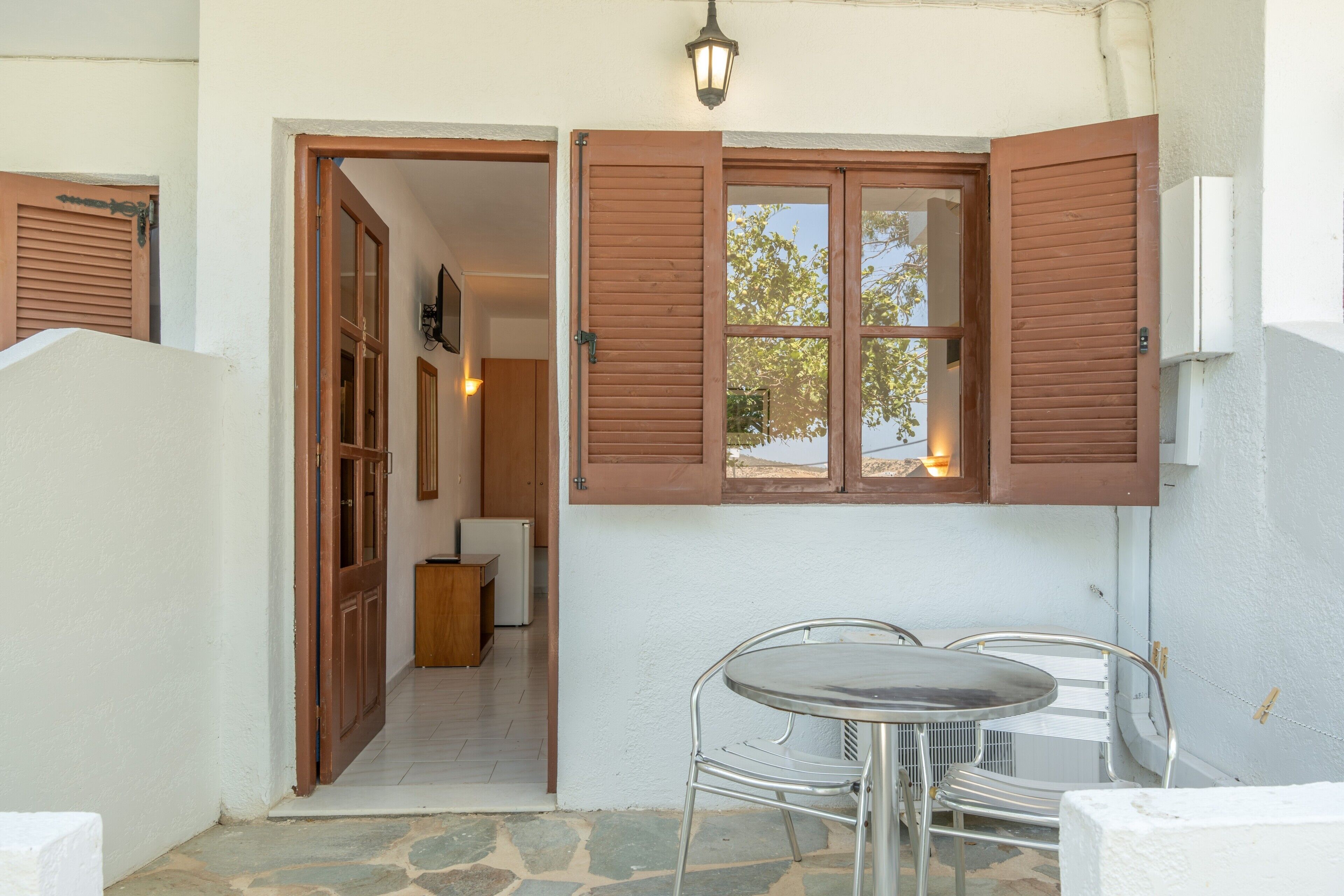 A room with a dining table and chairs, a wooden door, and a window with shutters.