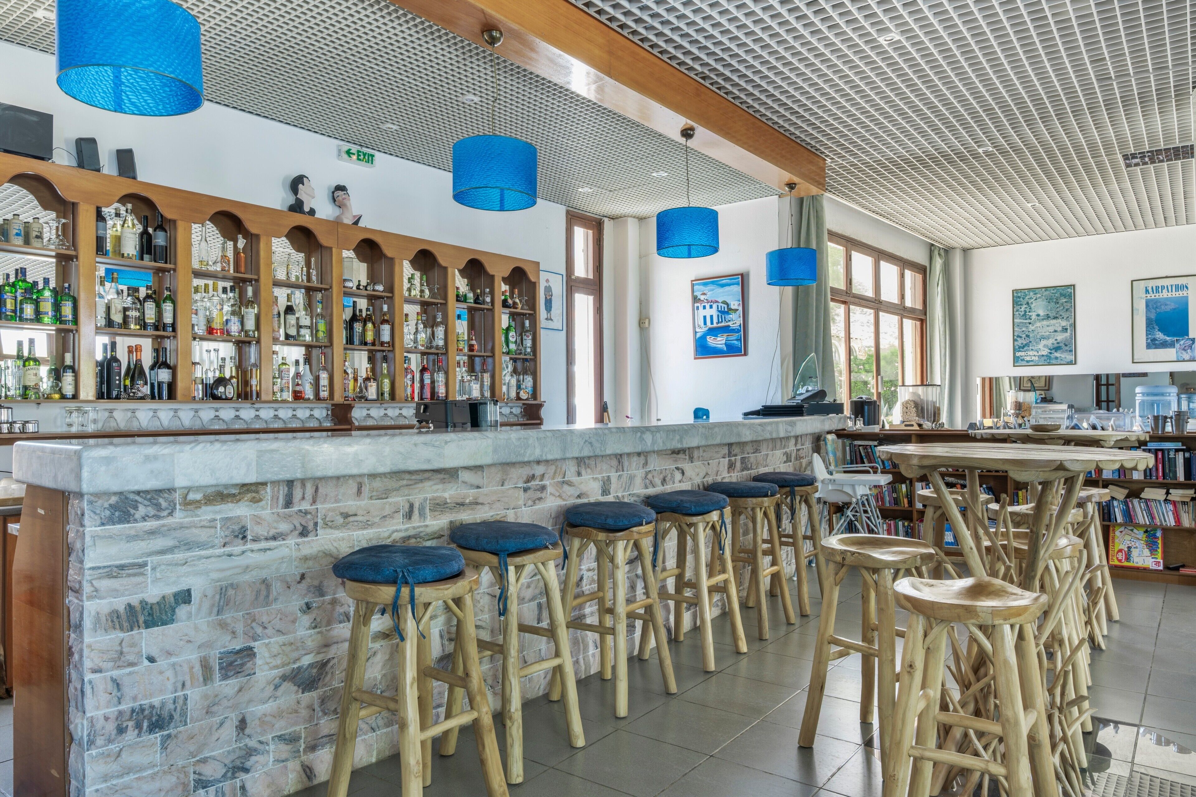 Un espace bar avec des tabourets en bois, un comptoir en marbre et une variété de bouteilles.