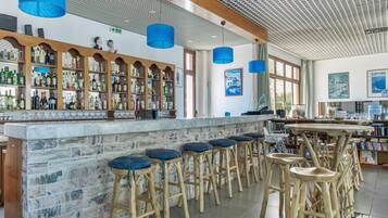 Un espace bar avec des tabourets en bois, un comptoir en marbre et une variété de bouteilles.