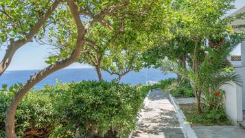 Un chemin de pierre mène à un bâtiment blanc d’où l’on a vue sur la mer.