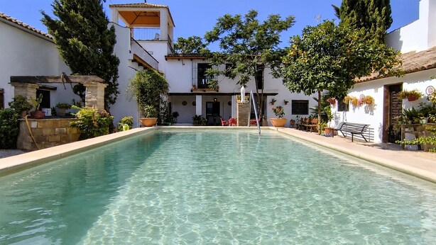 A clear pool with a white building in the background, a staircase, and potted plants. - Beautiful home in Puente Genil (Puente Genil)