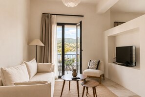 Ein modernes Wohnzimmer mit einer Couch, einem kleinen Tisch, einem Fernseher und einem Balkon mit Blick.