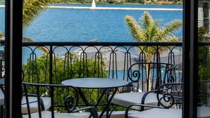Un balcone con tavolo e sedie, affacciato su uno specchio d'acqua e un paesaggio collinare.