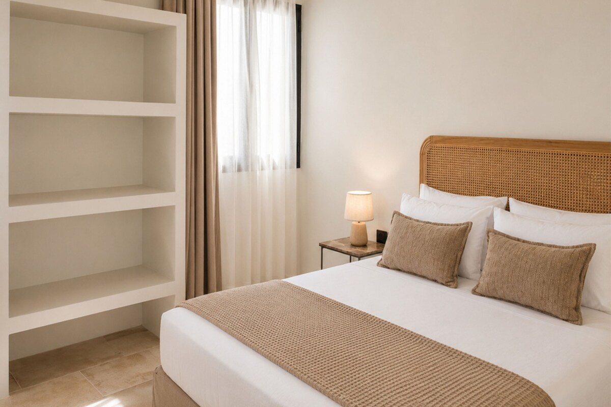 Ein Hotelzimmer mit einem Bett, einem Nachttisch mit Lampe, einem Kleiderschrank und einem Fenster mit Vorhängen.