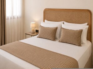 Ein Bett mit einem gewobenen Kopfteil, einer Nachttischlampe und zwei Kissen.