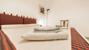 A neatly made bed with a plaid bedspread, a white pillow, and a folded towel. - Campiello Chiesa, Venezia (Venice)