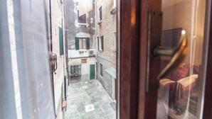 A narrow alleyway with a door leading to a room. - Campiello Chiesa, Venezia (Venice)