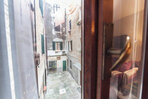 A narrow alleyway with a door leading to a room. - Campiello Chiesa, Venezia (Venice)