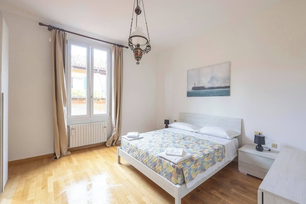 Ein Schlafzimmer mit Bett, Nachttisch, Lampe und einem Bild an der Wand.