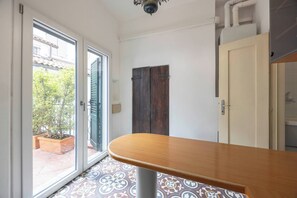 A room with a wooden table, a sliding glass door, a dark wooden door, and patterned floor tiles.