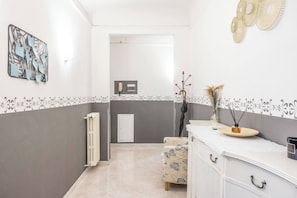 A modern bathroom with a white vanity, a radiator, and a decorative wall piece. - San Marco, Florence By Short Holidays (Florence)