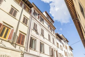 Ein mehrstöckiges Gebäude mit Balkonen und Fensterläden, mit blauem Himmel.