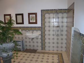 Ein Badezimmer mit Waschbecken, Dusche, gefliesten Wänden und gerahmten Bildern.