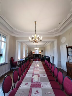 Ein langer Esstisch mit roten Stühlen, einer Chandelier und einem Weihnachtsbaum.