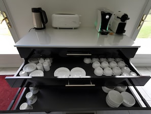 Eine Küche mit Kaffeemaschine, Toaster und einem Schubladenorganisator für Teller und Tassen.