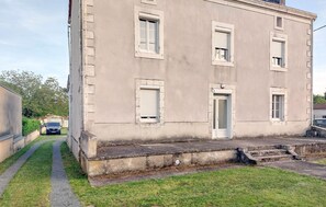 A building with a flat facade, multiple windows with shutters, a door, and a small front yard with a pathway. - 1 bedroom amazing apartment in savignac-les-églises (Savignac-les-Églises)