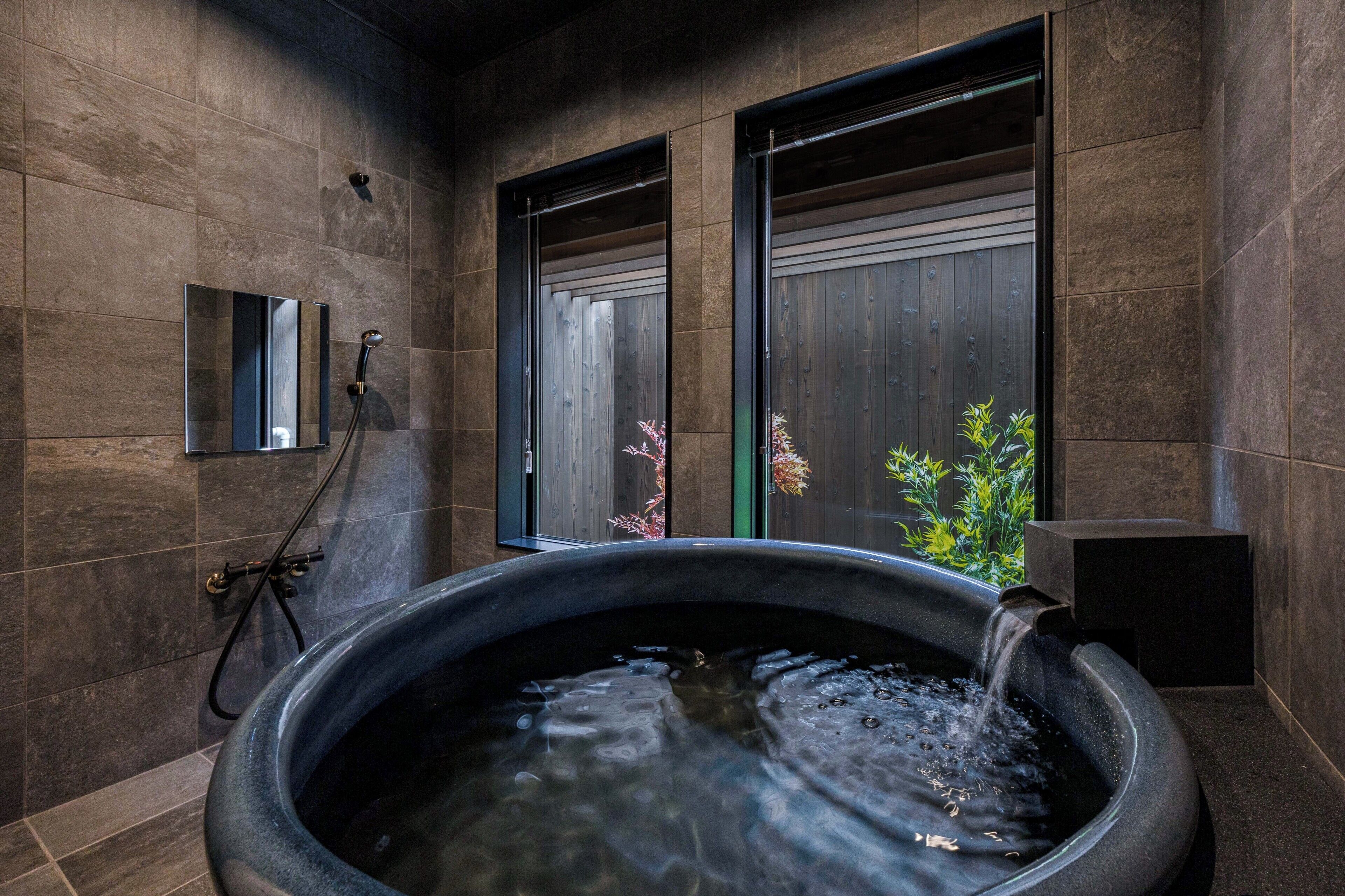 A modern bathroom with a large bathtub, a shower area, and a small mirror.