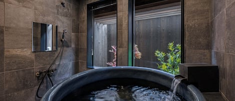 A modern bathroom with a large bathtub, a shower area, and a small mirror.