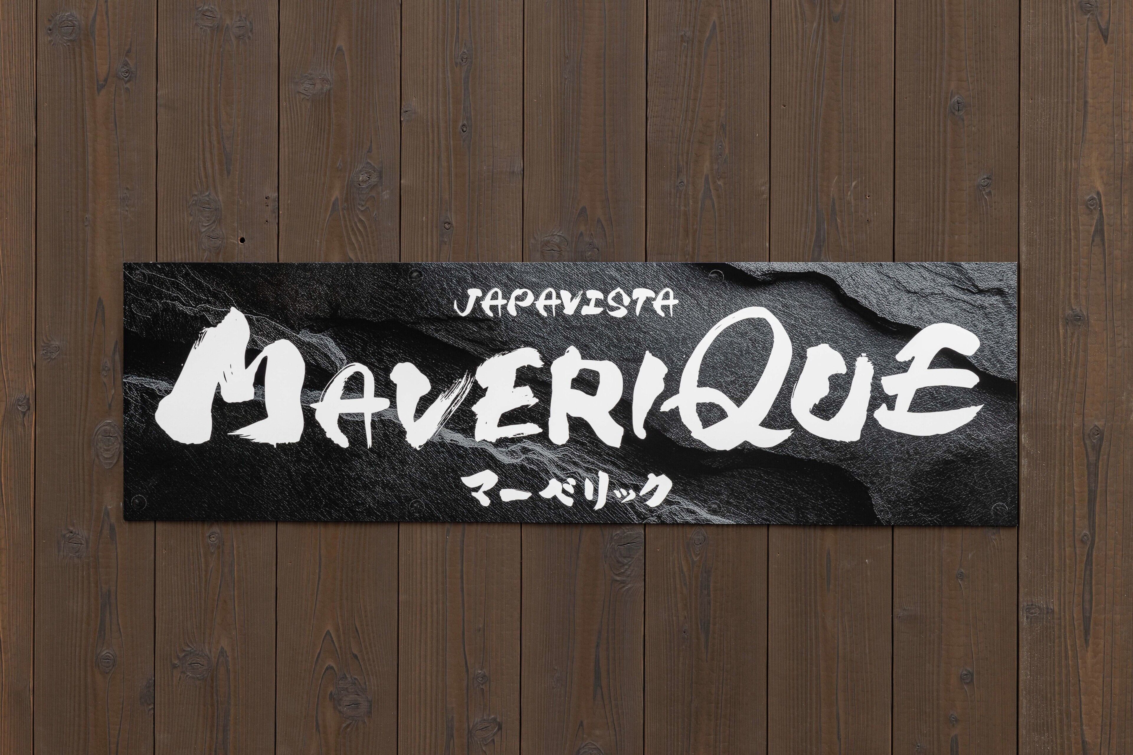 A black sign with white Japanese text on a wooden background.