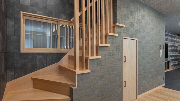 Een modern interieur met een houten trap, een deur en een raam met jaloezieën.
