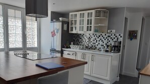 Eine moderne Küche mit weißen Schränken, einer schwarz-weißen Schachbrettküchenrückwand und einer eingebauten Kochinsel mit einem blauen Notizbuch.