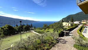 Un court de tennis, un chemin de pierre et une vue sur la mer et les montagnes.