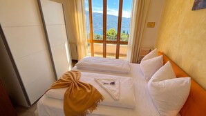 Une chambre d’hôtel avec un lit, une vue sur les montagnes par la fenêtre et un balcon.
