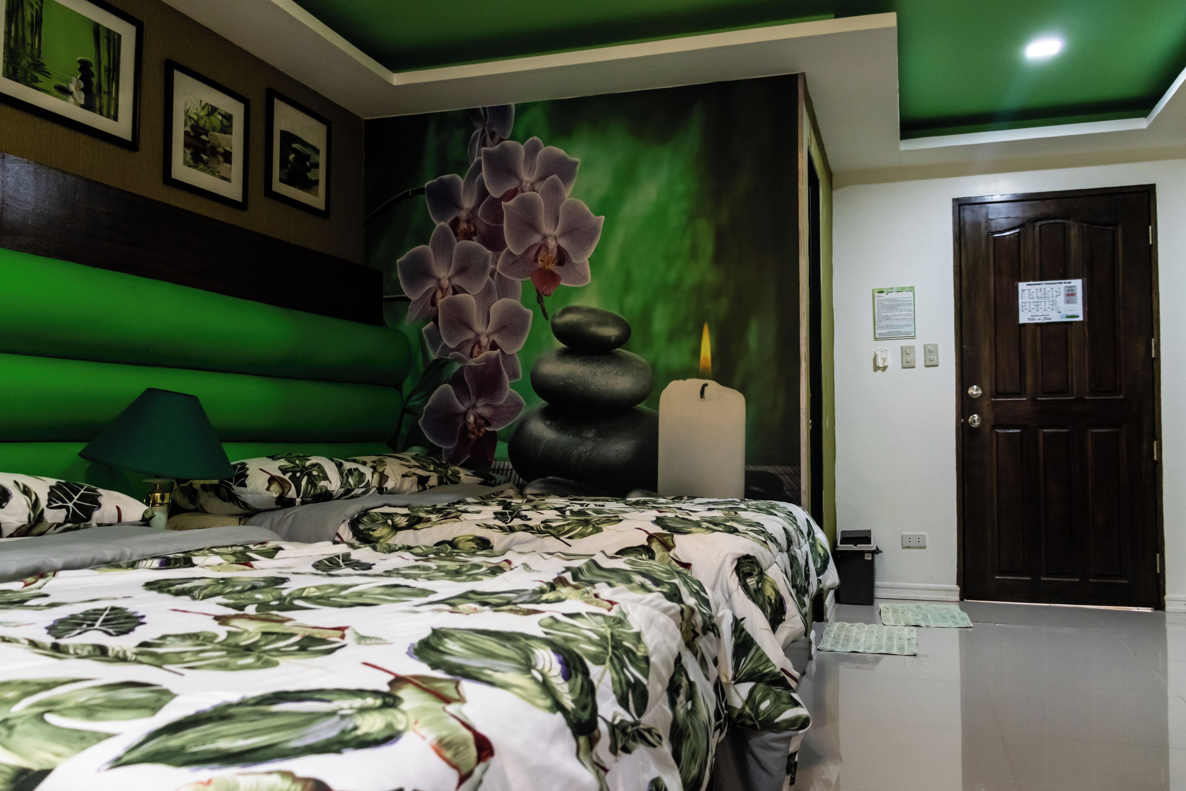 A bedroom with a bed, a green wall, a door, and a poster.