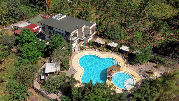 Una casa moderna con piscina rodeada de abundante vegetación.