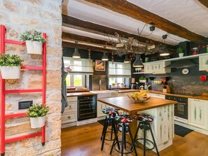 A kitchen with a stone wall, wooden beams, hanging plants, a red ladder, and bar stools. - Villa ARtIEN, 4 bedroom house with swimming pool (Baderna)