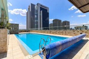 Une piscine sur le toit d’un immeuble, avec en arrière-plan le bâtiment d’un hôtel Marriott.