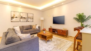Una sala de estar moderna con un sofá, una mesa de centro, un televisor y una planta.