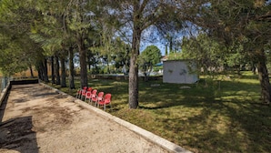A gravel path with red chairs, trees, and a small shed. - Pool & Garden House Jaga (Polaca)