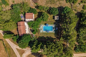 An aerial view of a property with a swimming pool, a fenced yard, and a building with a red roof. - Pool & Garden House Jaga (Polaca)