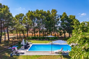 A swimming pool with lounge chairs and umbrellas, surrounded by trees and a grassy area. - Pool & Garden House Jaga (Polaca)