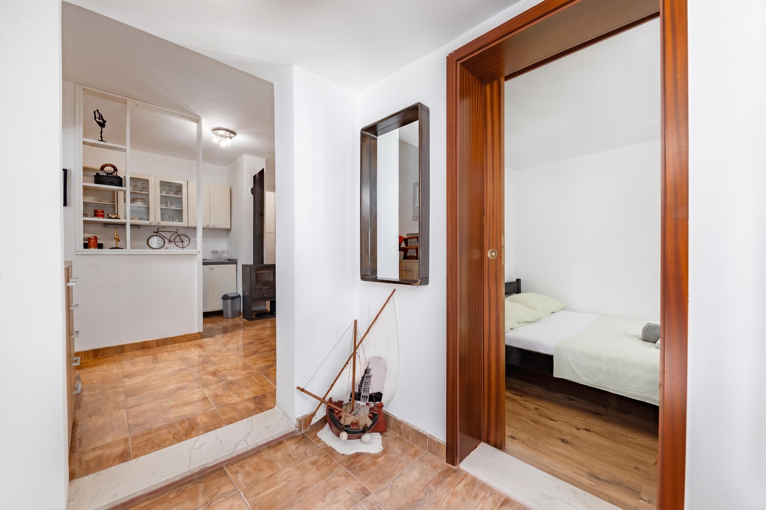 A bedroom with a wooden door, a bed with white bedding, and a small bedside table.