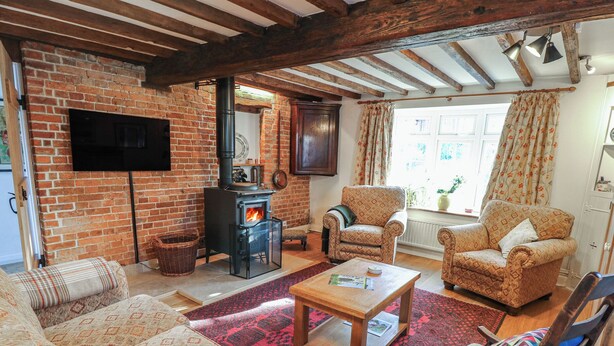 A cozy living room with a brick fireplace, wooden beams, a television, and patterned furniture. - 5 Castle Street (Newport)