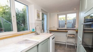 A kitchen with a built-in dishwasher, a window with a view of greenery, and a white radiator. - 5 Castle Street (Newport)