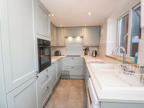 A compact kitchen with a built-in oven, a sink, and a window. - 5 Castle Street (Newport)
