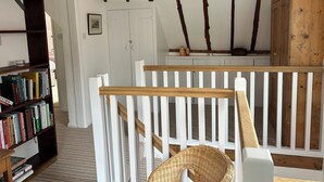 A room with a wooden staircase, a white railing, a bookshelf, and a white door. - 5 Castle Street (Newport)