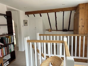 Ein Zimmer mit einer Holztreppe, einem weißen Geländer, einem Bücherregal und einer weißen Tür.